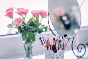 dressing table with flowers and makeup brushes on it, looks glam