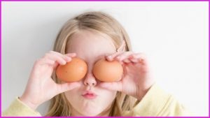 girl holding eggs to her eyes before cooking