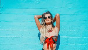 lady full of confidence wearing sunglasses and summer outfit leaning against a wall