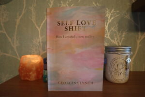 self love shift book on a shelf next to jar tealight holder and Himalayan rock salt tealight holder