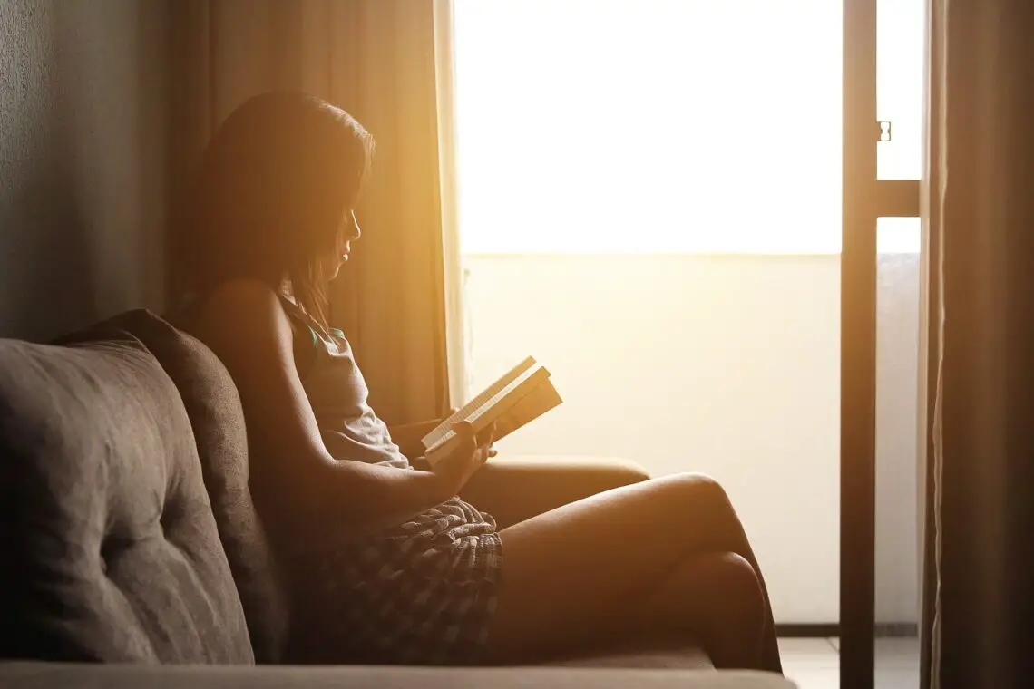 Woman sat reading a book in front of a window