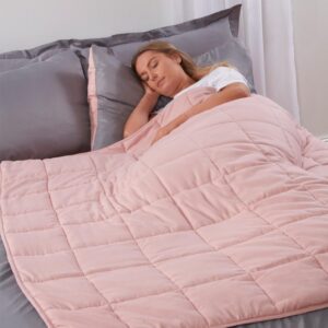 Woman lying under a pink weighted blanket