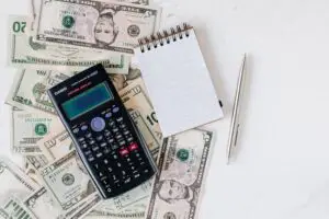 calculator, notebook, and money to log changes in a money mindset