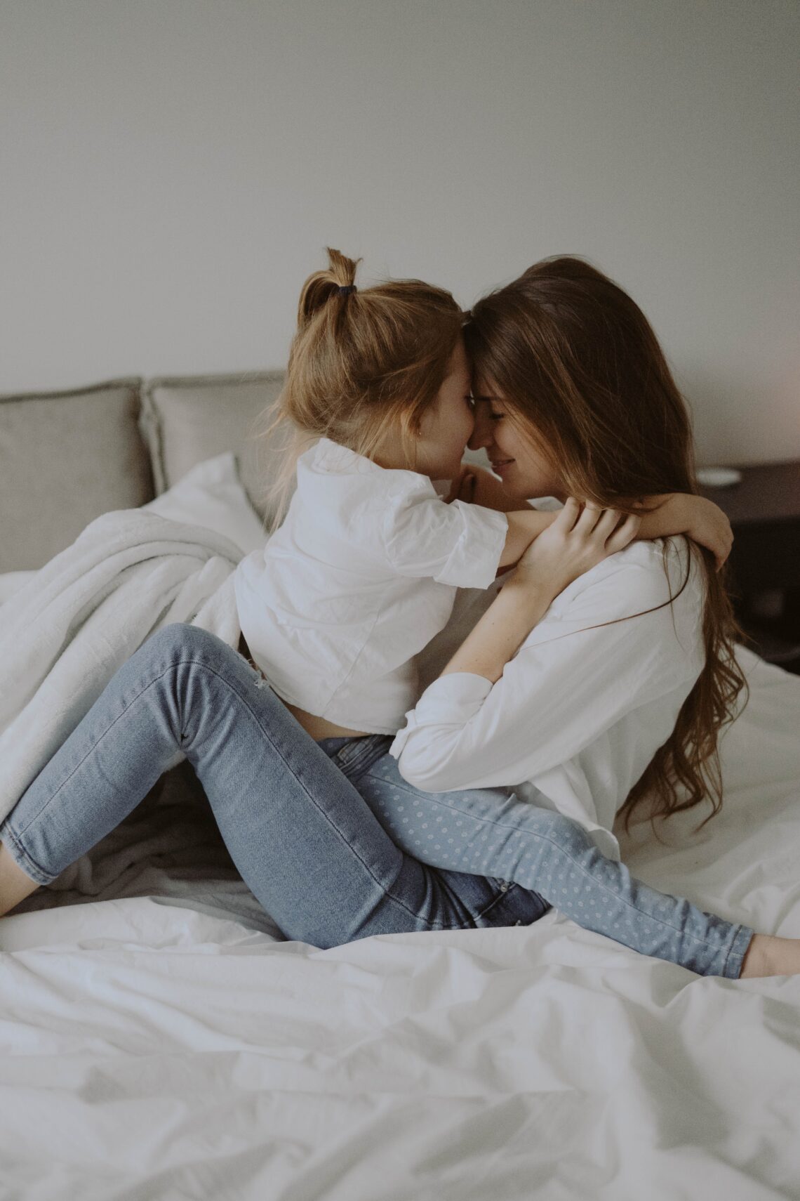 Mother and daughter hugging on sofa