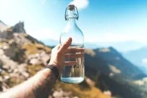 water bottle in front of mountain background: ways to look after yourself this summer