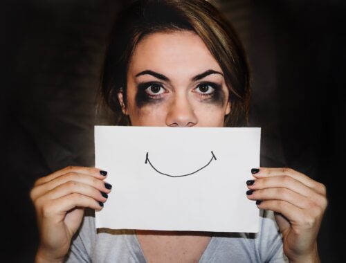 person with paper and drawn on smile, mental health