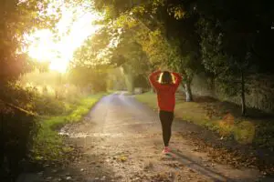 person on an Autumn run, surrounded by trees and sunshine