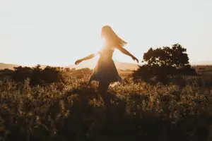 woman walking in a field with setting sun in background helping her in taking care of her mind and body