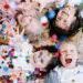 four happy children lying on the floor face up with confetti falling down on them showing their development
