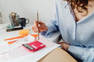 woman sat at desk working out bills on a calculator