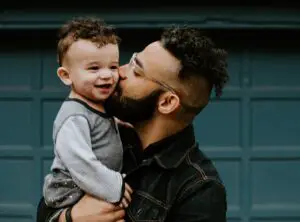 man kissing child in his arms