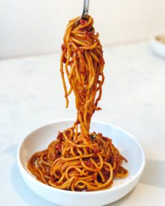 a bowl of spaghetti bolognese with a fork holding some of the pasta out of the bowl