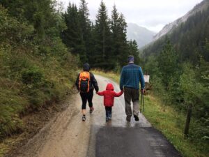 three people on a walk - two adults and a child - wearing rain coats