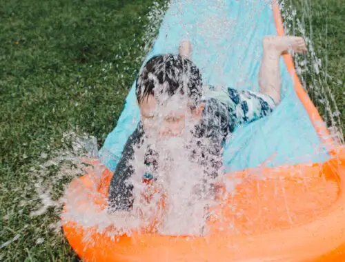 little boy sliding down a garden water slide