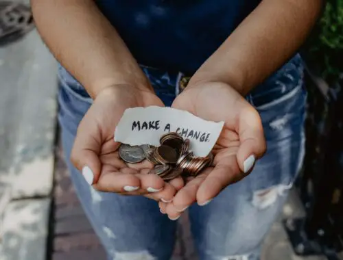 person holding out hands with money as a donation
