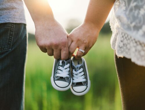 two people holding baby trainers between them while holding hands
